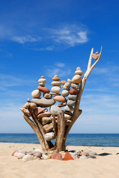 pile de pierres équilibrées multicolores sur un vieux accrocs en bois, sur un ciel bleu et fond de mer - balance simplicity nature beach photos et images de collection