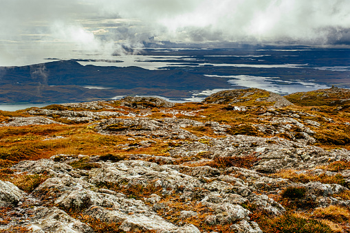 Thin vegetation, rocky, and landscape of water from the summit of Eabhal, Uist, Scotland.