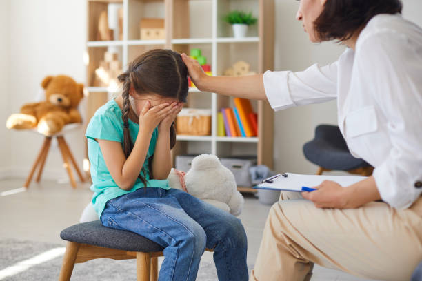 Little girl crying in psychotherapist's office sharing problems and concerns and seeking help