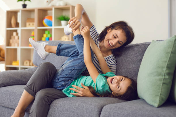 istock Smiling daughter lying on sofa, playing with mother and looking at camera at home 1283338020