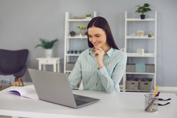istock Smiling woman looking at laptop and learning new information during online lesson 1283338137