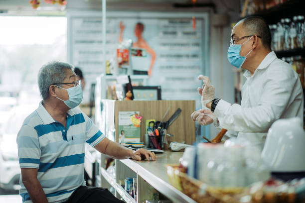 asian chinese male pharmacist assisting an active senior customer in front counter of chinese medicine shop - polo shirt two people men working imagens e fotografias de stock