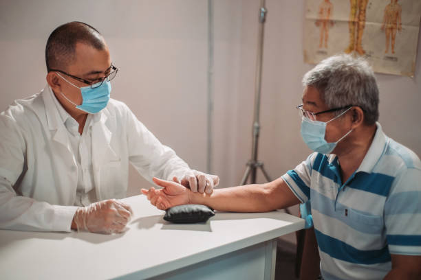 Asian chinese male acupuncturists taking pulse diagnosis works for his patient at chinese medicine shop stock photo