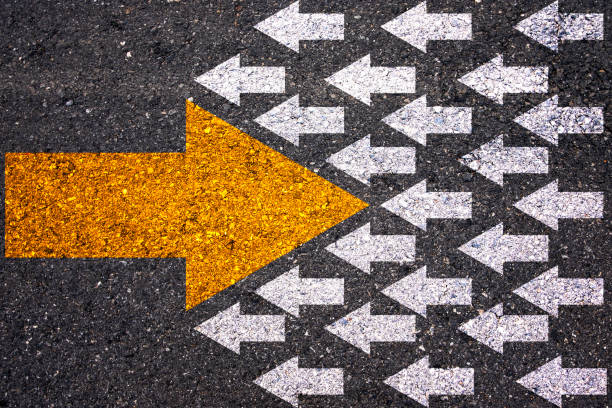 istock Different thinking and Business and technology disruption concept. Yellow big arrow opposite  direction with white arrow on road asphalt. 1283338525
