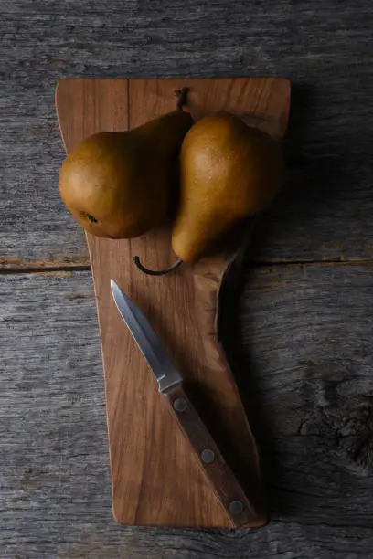 Bosc Pears on a cutting board with knife. overhead view in vertical format