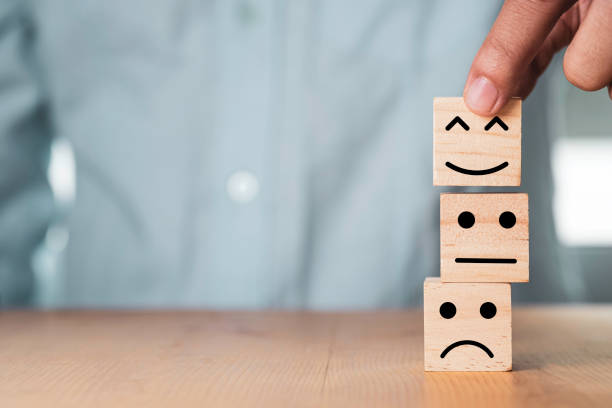istock Select emotion or mood concept , Hand holding smile face  or happy face which print screen on wooden cube block. 1283339968