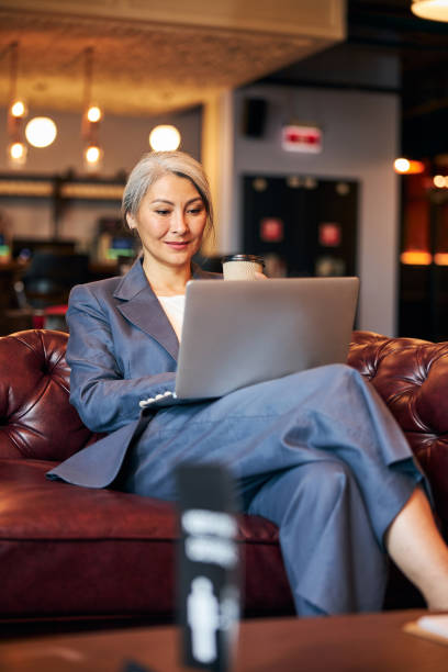 istock Beautiful woman sitting on sofa and working on laptop 1283340949