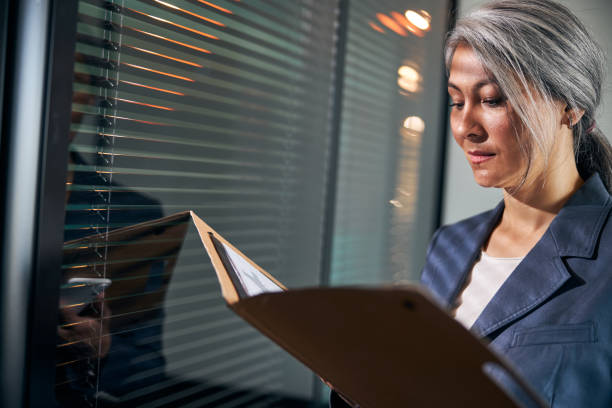 istock Beautiful woman holding folder with papers and cellphone 1283342247