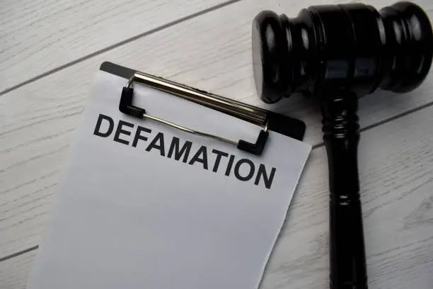 Photo of Defamation text write on a paperwork and gavel isolated on office desk.