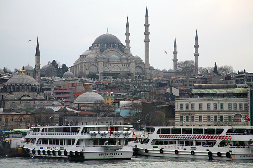 Istanbul,Turkey - January 2, 2015: Galata Tower Amidst Buildings In Front Of River Against Clear Sky In City. Beyoglu area viewed from Eminönü docks, Istanbul, Turkey The Galata Tower (Galata Kulesi in Turkish) — called Christea Turris (the Tower of Christ in Latin) by the Genoese — is a medieval stone tower in the Galata/Karaköy quarter of Istanbul, Turkey, just to the north of the Golden Horn's junction with the Bosphorus.