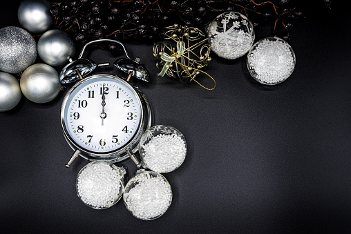 Alarm Clock and Bright Christmas Ornaments on Black Background