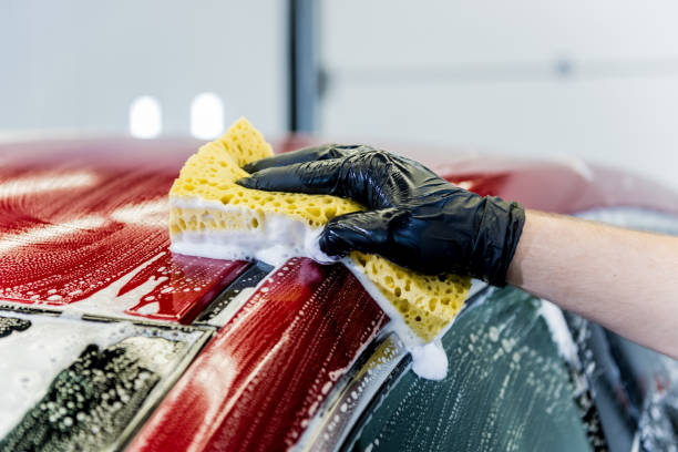 istock Worker washing red car with sponge on a car wash 1283346577