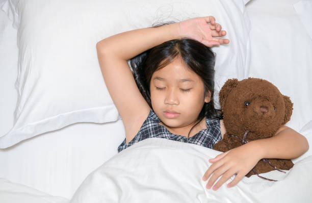 istock Cute little girl hugging teddy bear sleeping lay in  bed, 1283347499