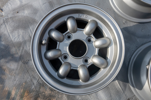 These are the Alloy wheel rims of a 1974 Classic Mini Cooper Innocenti 1300 Export undergoing refurbishment.  This is a close-up of the rims after preparation and with the silver alloy paint top coat applied.