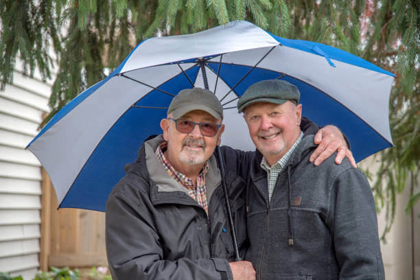 senior gay couple under an umbrella. - umbrella senior adult couple autumn imagens e fotografias de stock