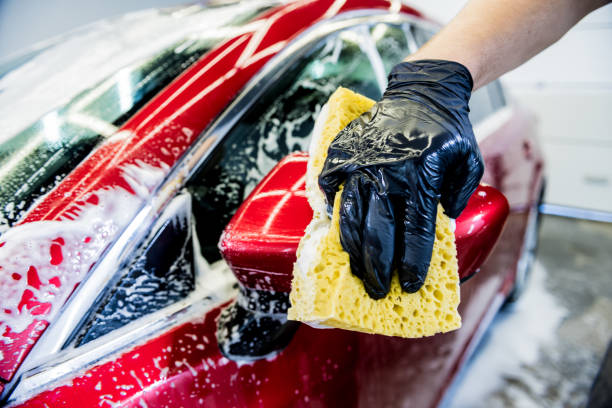 istock Worker washing red car with sponge on a car wash 1283349643