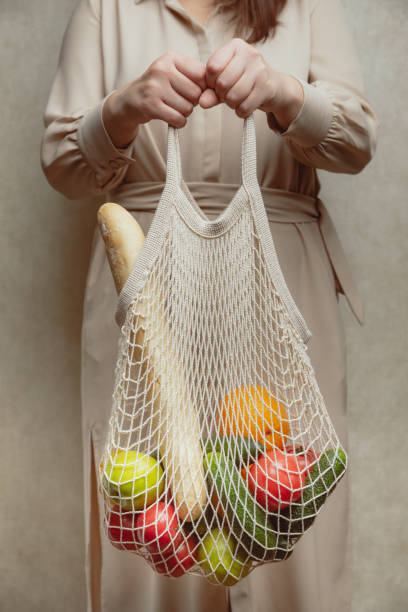 istock woman holding mesh shopping bag. 1283350219