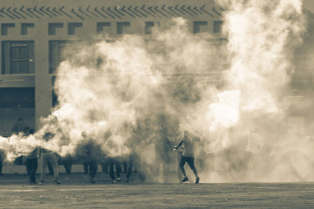Military police riot response to a protest with tear gas, smoke, fire, explosions. Political expression, riot, protest, demonstration and military concept. stock photo