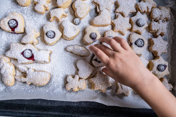 little kid's hand taking a freshly baked cookie at home - christmas child little boys peeking imagens e fotografias de stock
