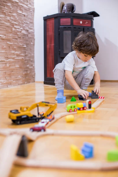 istock Beautiful little boy playing with a railroad train toy and plastic vehicle. 1283356246