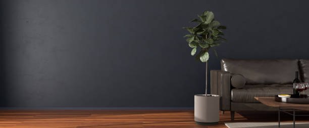 istock Elegant interior setting with wooden floor, dark wall, leather sofa, coffee table with wine and glasses, carpet and ficus tree. Sunlight falling in, copy space to the left - web banner size. 3d render. 1283356332