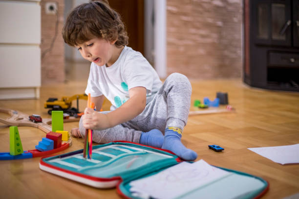 istock Beautiful toddler boy drawing using paper and crayons. 1283356339