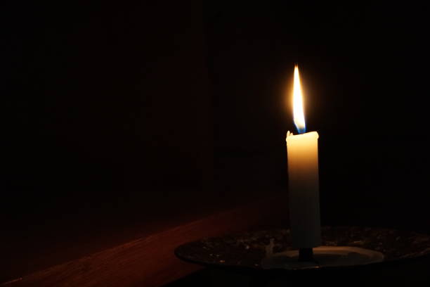 istock A single candle blowing in darkness. Its flame casts soft shadow, but is not strong enough to enlighten the space. 1283358899
