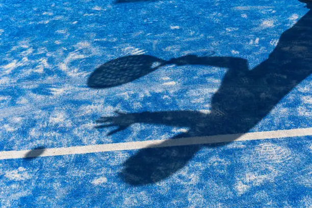Shadow of a man playing paddle on the paddle court