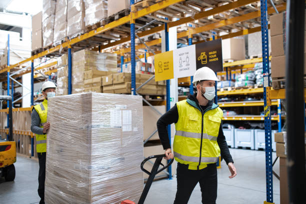 Group of workers with face mask working indoors in warehouse, coronavirus concept.