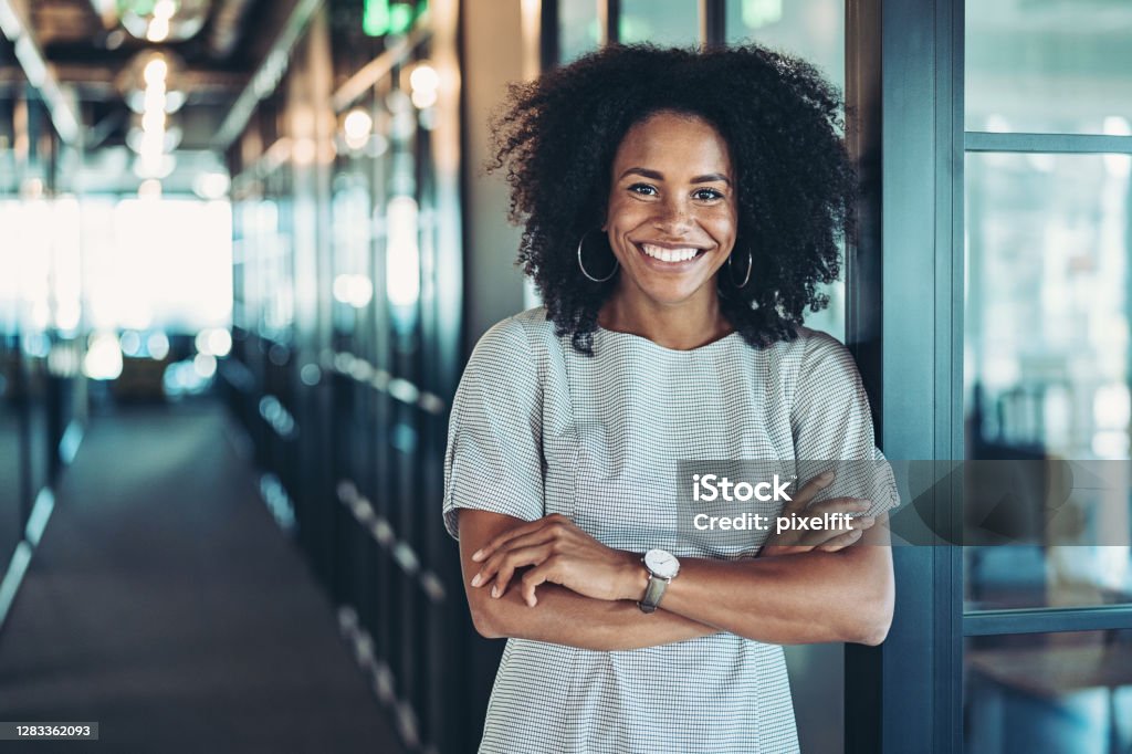 Young businesswoman standing in the corridor Portrait of a smiling businesswoman with arms crossed Women Stock Photo