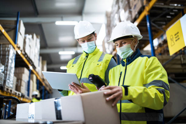 istock Workers with face mask working indoors in warehouse, coronavirus concept. 1283362705