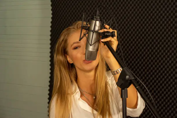 young attractive Caucasian woman musician singer in recoding studio with microphone. Performance arts concept.