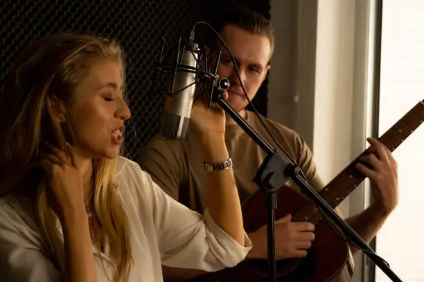 young attractive Caucasian woman musician singer in recoding studio with microphone. Performance arts concept.