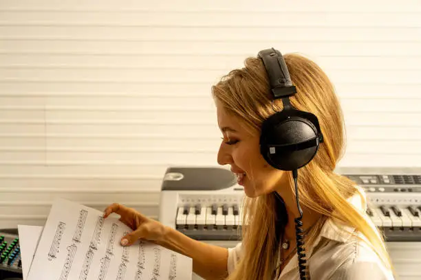 young attractive Caucasian woman musician singer in recoding studio with microphone. Performance arts concept.