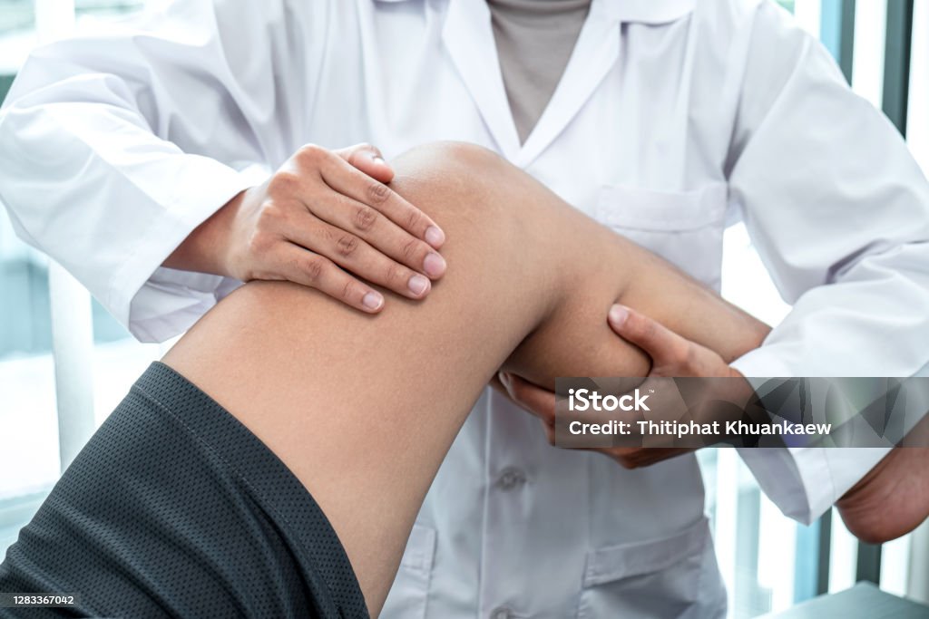 Female Physiotherapist working examining treating injured leg of patient, Doing exercises the Rehabilitation therapy pain his in clinic Female Physiotherapist working examining treating injured leg of patient, Doing exercises the Rehabilitation therapy pain his in clinic. Human Spine Stock Photo