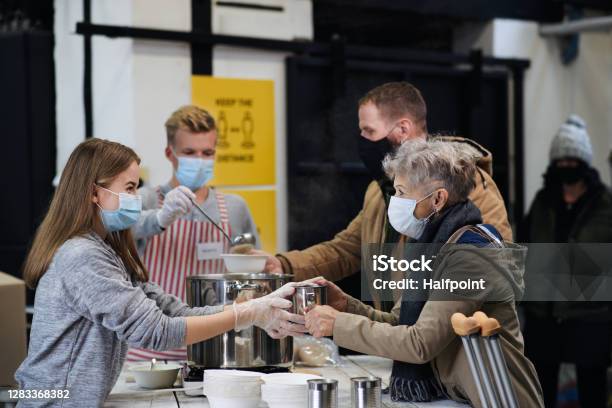 Volunteers Serving Hot Soup For Homeless In Community Charity Donation Center Coronavirus Concept Stock Photo - Download Image Now