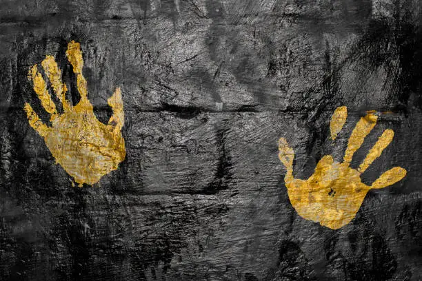 Photo of yellow print of two palms on a black wall