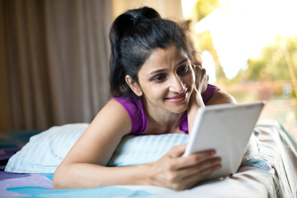 istock Woman using digital tablet lying on bed at home 1283369267