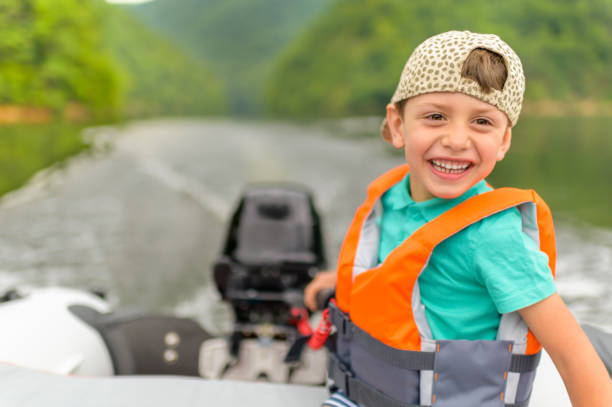 little boy driving the motorboat - sailing nautical vessel family lake stock-fotos und bilder