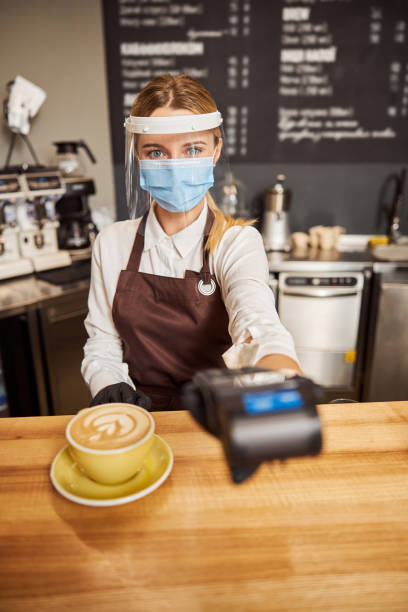 istock Charming barista in stylish uniform taking pos terminal for payment 1283370409