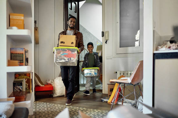 joven niño siguiendo a su padre en un nuevo apartamento en el día de mudanza - moving house physical activity moving van box fotografías e imágenes de stock