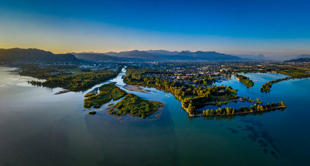 Aerial view of a sunrise at lakeside Aerial view of the Bregenzerach estuary in the morning at the shore of Lake of Constance in Austria. On the left side the city Bregenz, on the right side the village Hard estuary stock pictures, royalty-free photos & images