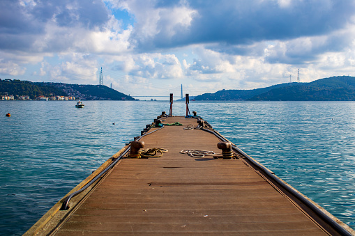 A perspective of a dock reaching to the cloudy blue sky while holding the sunshine on itself.