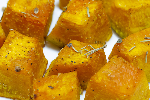 Baked pumpkin in a white plate. Side view. Pumpkin cooked in the oven. Cut pieces of pumpkin.A traditional autumn dish of baked pumpkin. Macro photography of food.