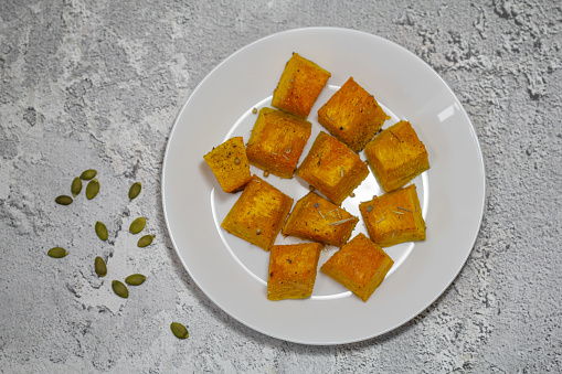 Baked pumpkin in a white plate. Pumpkin cooked in the oven. Cut pieces of pumpkin.A traditional autumn dish of baked pumpkin.