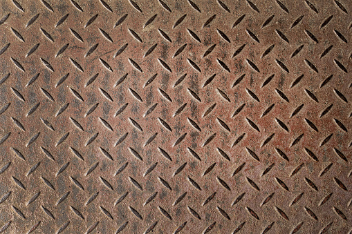 Abstract background of old rusty diamondplate rusty metal panel. Grunge brown rough grip industrial steel texture pattern.