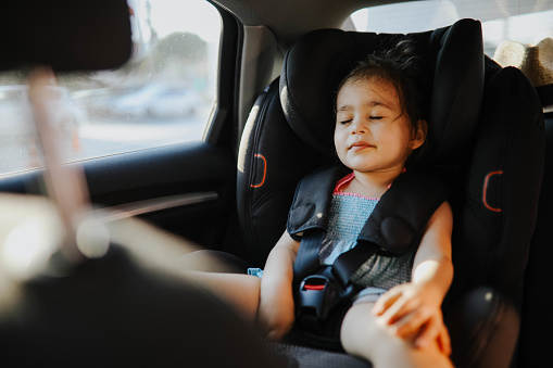 A Baby Girl asleep in her car seat.