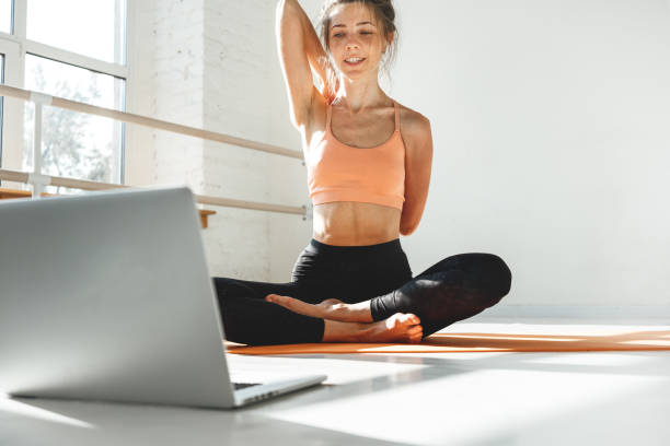 istock Fitness instructor having virtual yoga class using video call on laptop. Remote yoga teacher leads a lesson for people 1283384365
