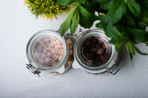 Balanced diet, Close view of Glass jars with Superfoods, hazelnuts, walnuts, decorated with mint leaves, flat-lay on light background with copy space.