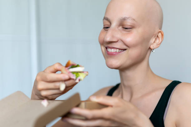 젊은 성인 아름다운 백인 대머리 면도 머리 여성 초상화는 집에서 점심 샌드위치를 먹는 즐길 수 있습니다. 유방암 생존자 영양 건강 한 다이어트 인식. 체모테라피 탈모증 - anti cancer 뉴스 사진 이미지